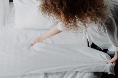 Someone carefully inspecting bedsheets for bed bugs.