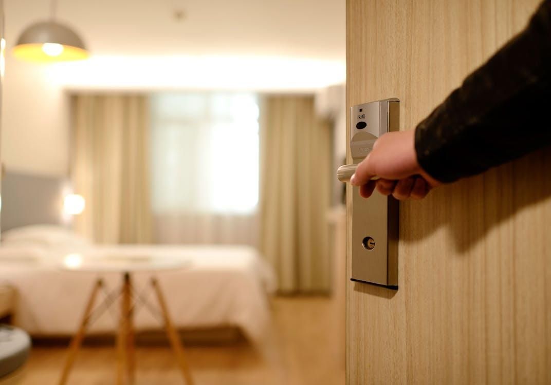 A person opening the door to their hotel room.