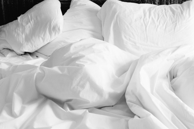 A messy bed with white linen.